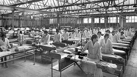 Veel vrouwen achter een strijkplank in de fabriekshal
