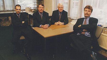4 mannen zittend achter een bureau