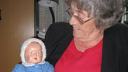 Anuscha houdt een oude pop uit de poppenfabriek ANJO vast.
